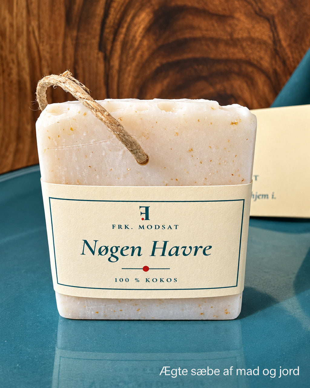 Nøgen Havre, lys kokossæbe med synlige havrekorn, hampesnor og kartonbånd, set forfra på en teal tallerken