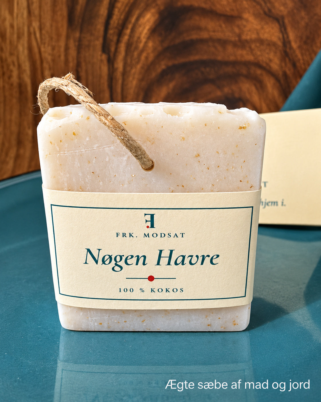 Nøgen Havre, lys kokossæbe med synlige havrekorn, hampesnor og kartonbånd, set forfra på en teal tallerken