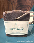Nøgen Kaffe, mørkebrun kokossæbe med synlig kaffe, hampesnor og kartonbånd, set forfra på en teal tallerken